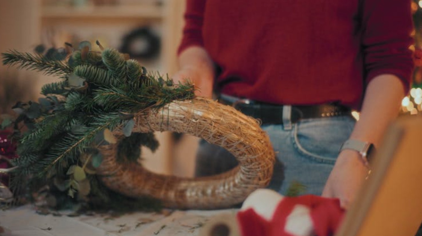 Women working together with focused expressions as they carefully craft their Christmas wreaths during the workshop