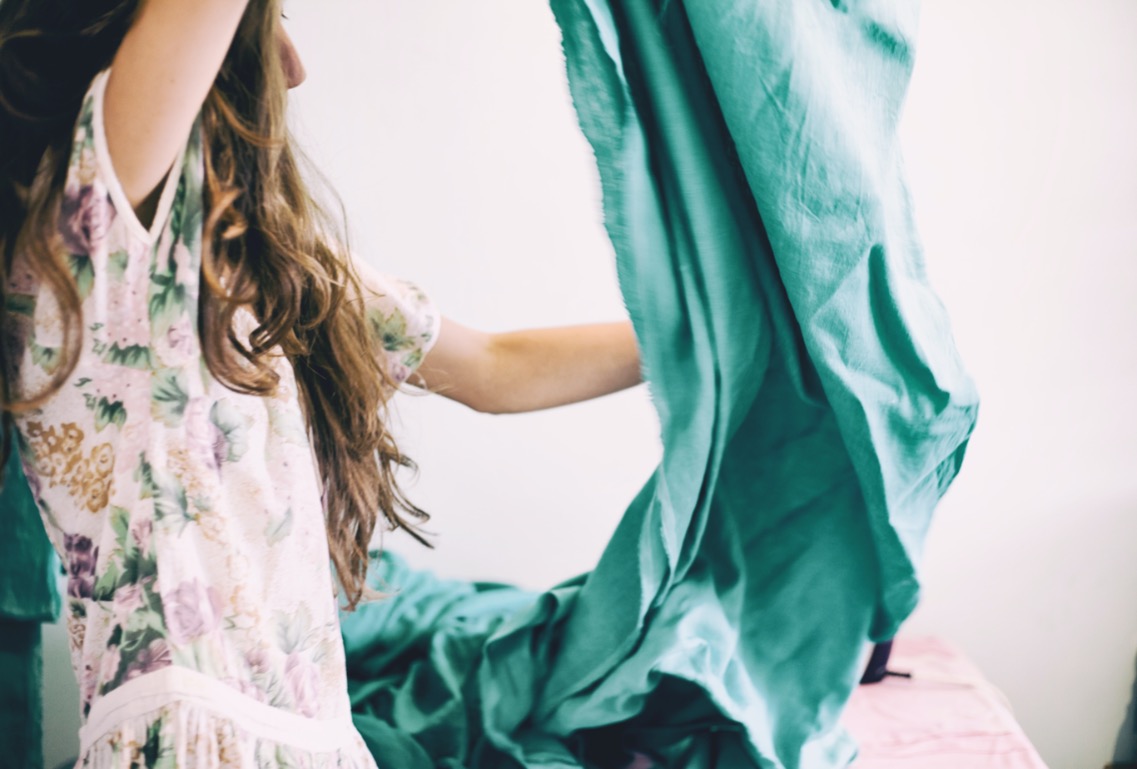 Woman smiling while running her hands through colorful fabrics during a creative workshop