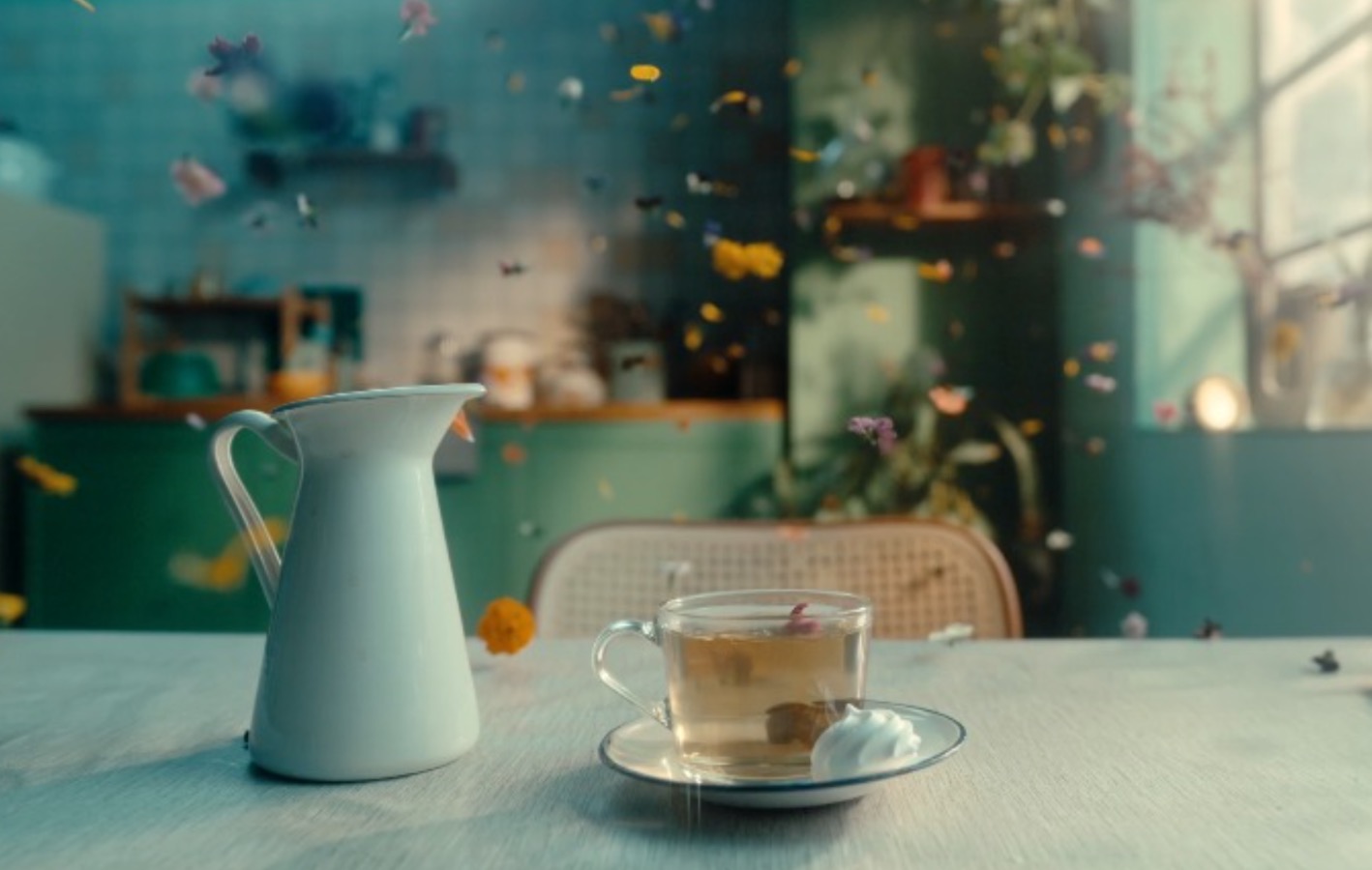 A cozy scene with a cup of tea on a saucer, accompanied by a white ceramic jug on a wooden table. Soft light filters through the room, with delicate flower petals floating in the air, creating a warm and inviting atmosphere.