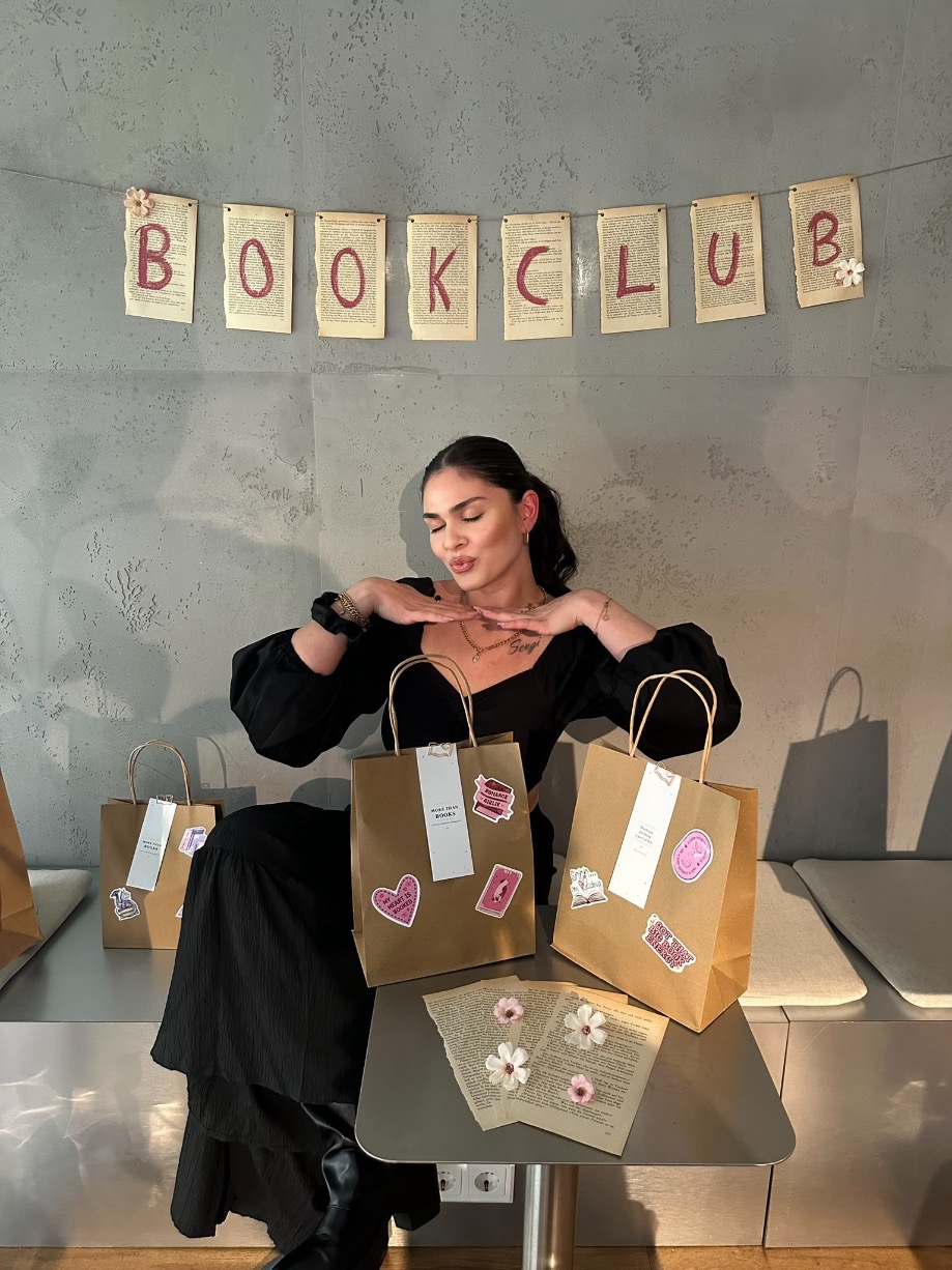 Franzi with More Than Books bags beneath a Book Club banner