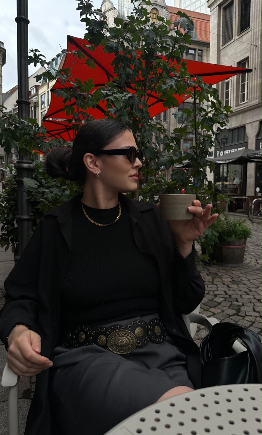 Franzi holding a coffee cup at an outdoor table