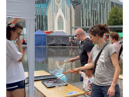 Kind und Erwachsene machen riesige Seifenblasen auf dem Leipziger Kinderfestival