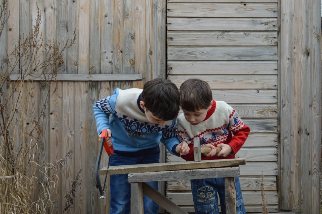 Zwei Kinder sägen und hämmern gemeinsam an einem kleinen Holzprojekt