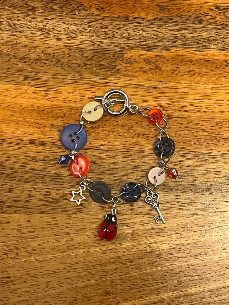 Ein selbst gemachtes Armband aus bunten Knöpfen und kleinen Anhängern auf einem Holztisch