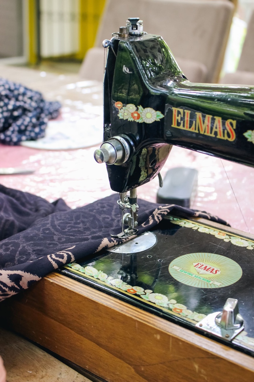 Eine historische Nähmaschine näht gemusterten Stoff bei einem Nähworkshop