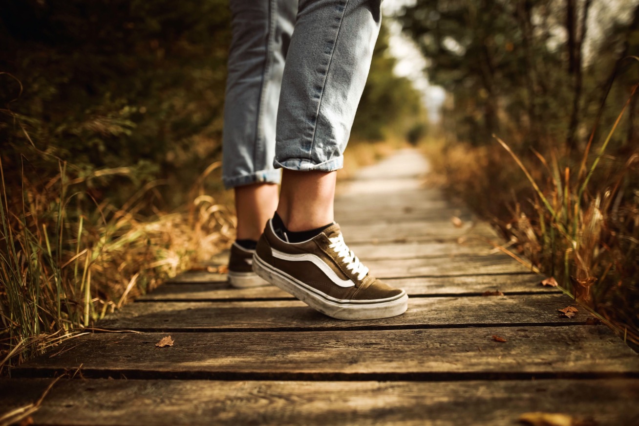 Eine Person startet auf einem Holzsteg zu einer Wanderung in der Natur